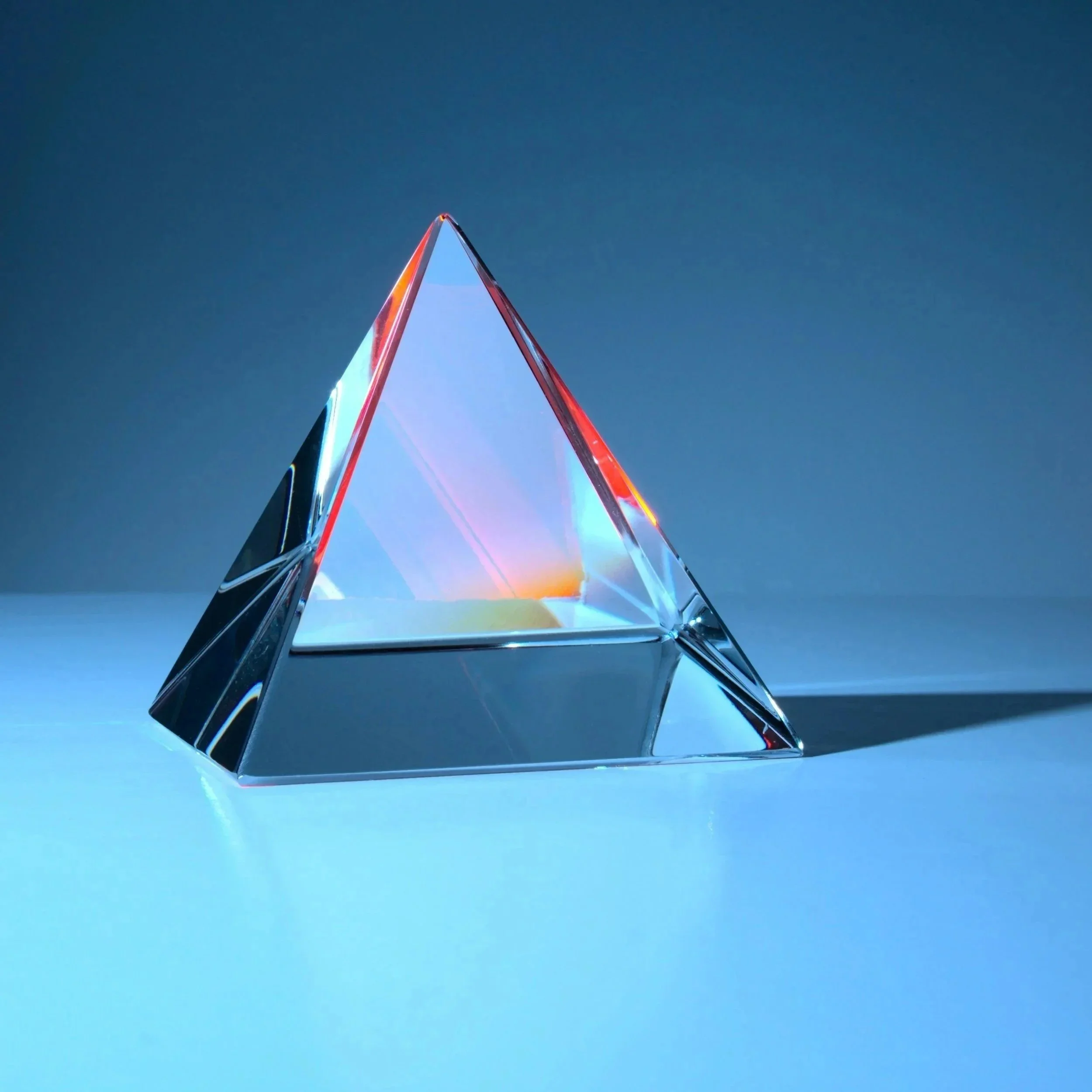 Une pyramide en verre, réfraction de la lumière, sur fond sombre.