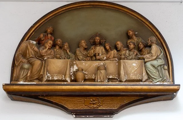 Wooden sculpture of The Last Supper depicting Jesus and his twelve apostles sitting around a table.