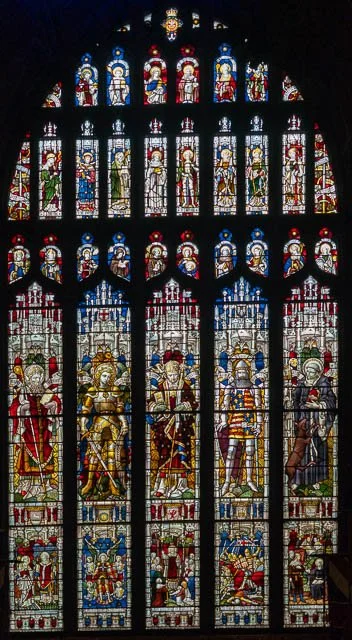 Colorful stained glass window depicting religious figures and scenes in Gothic style.