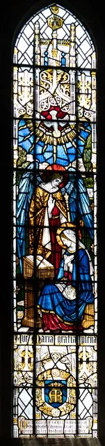 Stained glass window featuring a white lion with a crown and a shield, a knight in armor with a red and blue robe, and religious symbols and heraldic designs.