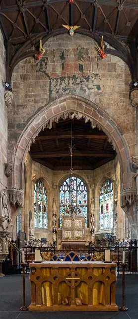 Interior of a historic church with stained glass windows, an altar, and religious decorations.
