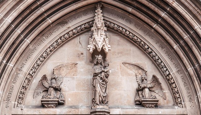 Religious stone carvings including a central Madonna and Child figure with two angels on either side