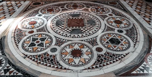 Close-up of a decorative Roman mosaic floor with geometric patterns and star designs.