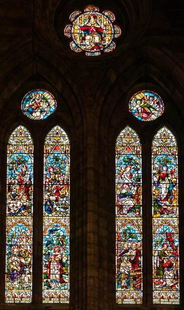 Colorful stained glass windows depicting biblical scenes in a church.