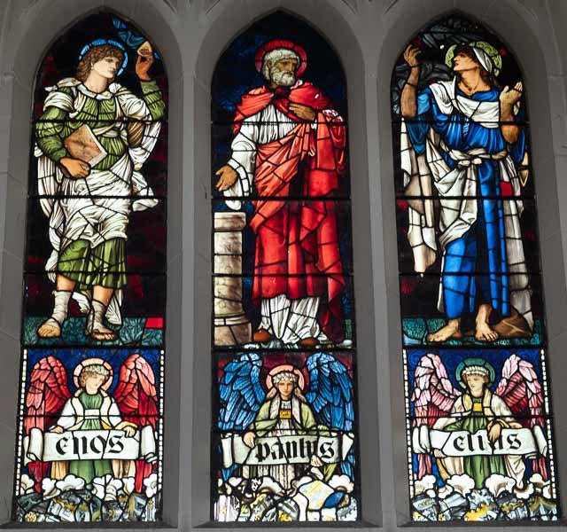 Colorful stained glass windows depicting three religious figures, each with wings and a name banner reading 'angels' in various languages.