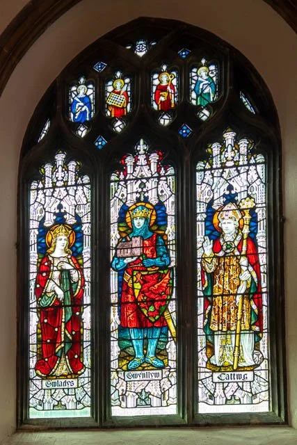 Stained glass window depicting three crowned queens or noblewomen, each labeled with their names: Gloradys, Gwynnlyu, and Cattina, with smaller angelic figures at the top.