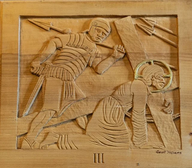 Carved wooden relief depicting a soldier and a woman, with a halo around the woman's head, in a biblical scene, with Roman numeral III at the bottom and signature 'Geoff Williams'.
