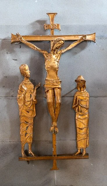 Wooden sculpture of Jesus Christ on the cross with two women figures standing on either side.