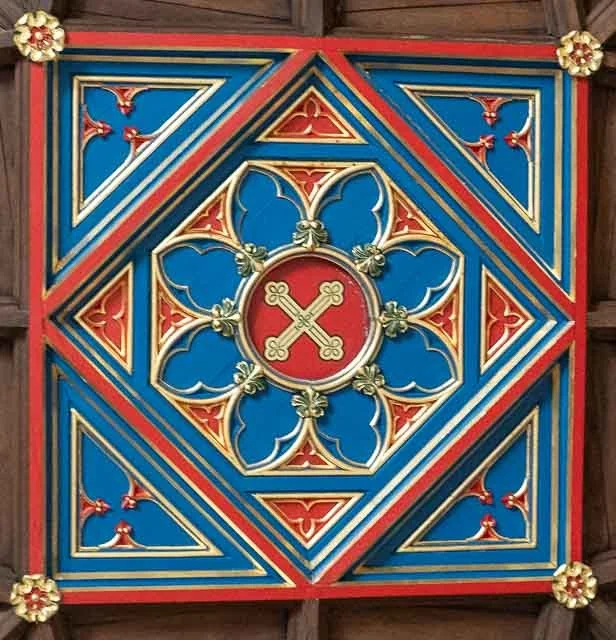 Decorative stained glass window with geometric patterns and a central circle with crossed keys, featuring red, blue, and gold colors.