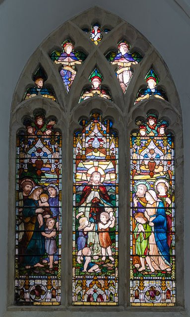 Colorful stained glass window with various religious figures and scenes, including Jesus, angels, and saints.
