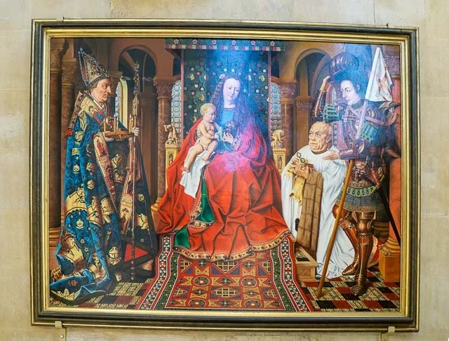 Painting of a regal scene depicting a seated woman in red robes holding a child, flanked by a king in royal attire on the left and a knight in armor on the right, set in an ornate room with patterned rugs and decorative elements.