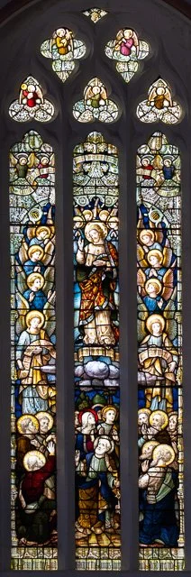 Stained glass window depicting Jesus Christ surrounded by angels and saints.