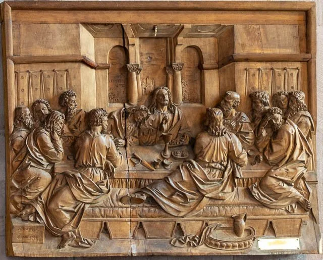 Wooden relief sculpture of The Last Supper scene with Jesus and twelve disciples seated around a table.