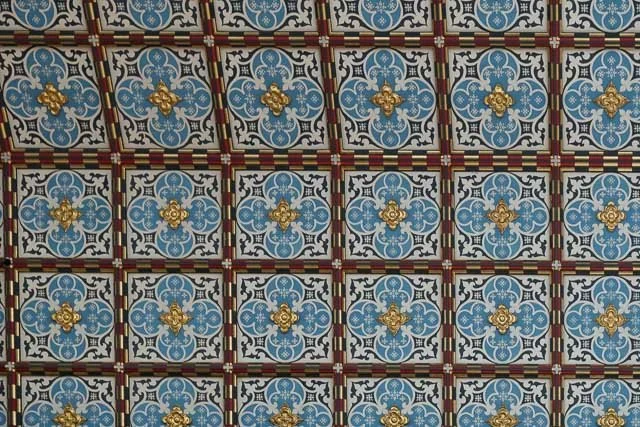 Patterned ceiling tiles with blue, black, white, gold, and red geometric and floral designs.
