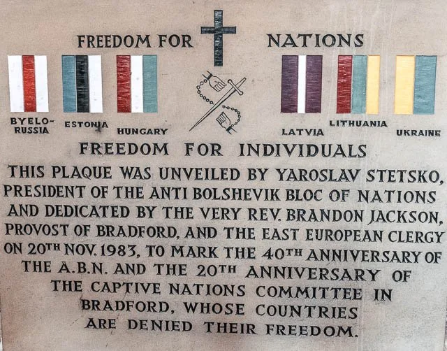 Plaque with the heading 'Freedom for Nations' featuring flags of Estonia, Hungary, Latvia, Lithuania, Ukraine, and Russia accompanied by a small cross and banner in the center. The plaque commemorates the unveiling by President Yaroslav Stetsko and t