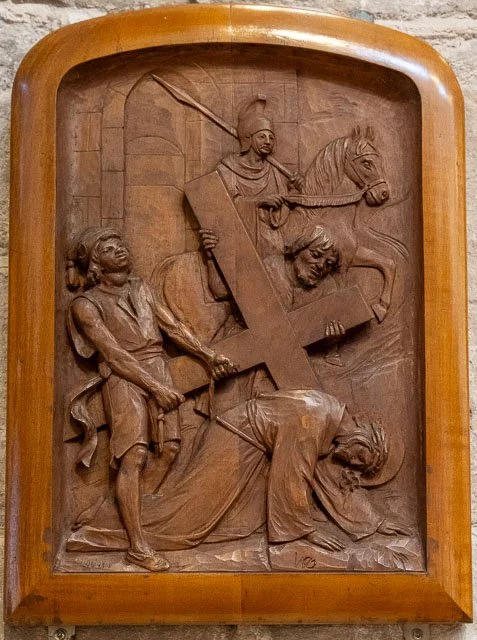 Wooden relief sculpture depicting a biblical scene of a man leading a slave and another person carrying a cross.