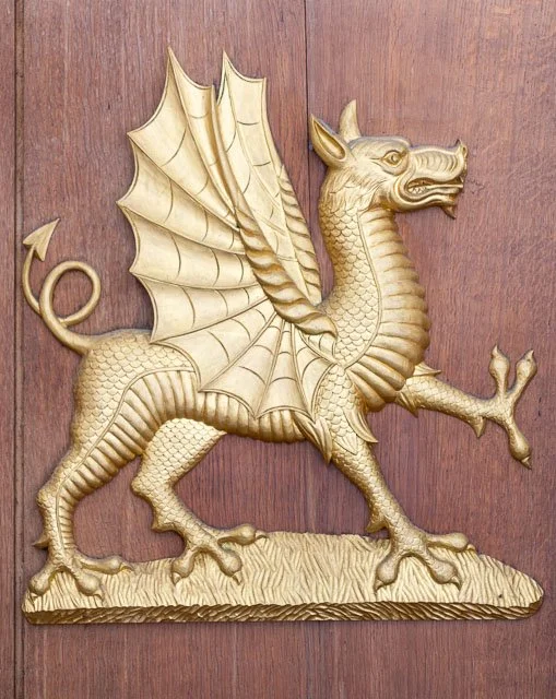 Decorative golden dragon sculpture mounted on a wooden surface.