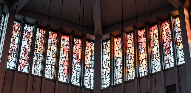 Colorful stained glass windows with abstract patterns in a church or cathedral.
