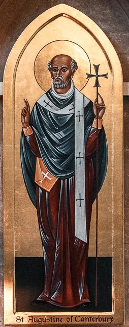 Painting of St. Augustine of Canterbury, a Christian saint, depicted with a halo, holding a staff with a cross, dressed in robes, standing against a gold background.