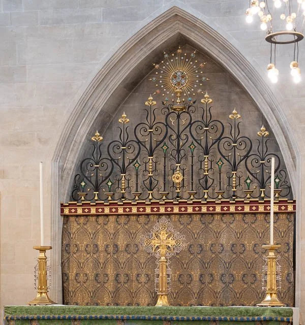 Religious altar inside a church with ornate ironwork, gold accents, and candles.