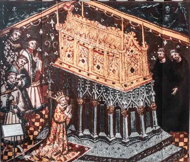 Religious scene depicting a church or cathedral interior with a choir of children on the left, a kneeling young girl in ornate robes in prayer, and two adults standing on the right near a large, decorated golden canopy or throne.