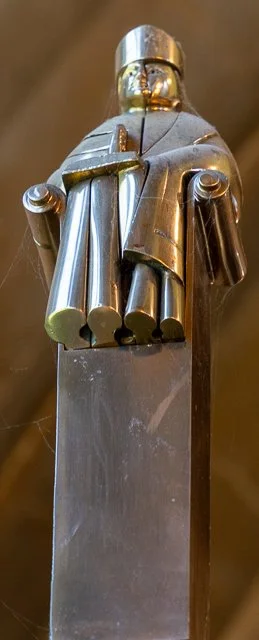 Close-up of a metallic sword hilt with a unique design, viewed from below.
