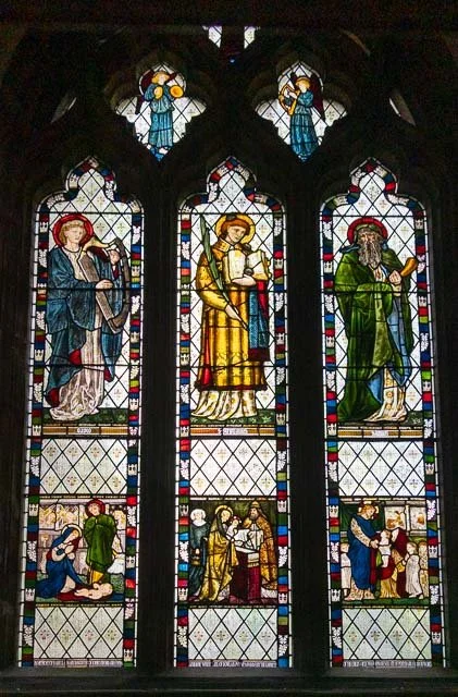 Stained glass church window with religious figures and scenes.