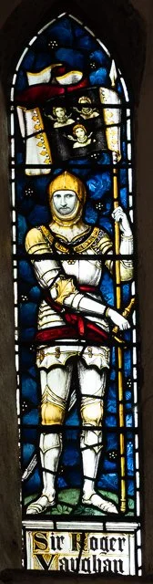 Stained glass window depicting Sir Roger Newsham in medieval armor, holding a sword and shield, with a harp and dragon at the top.
