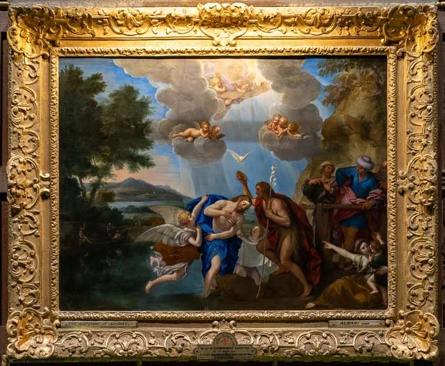 Religious painting depicting baptism scene with figures in water, including a man in blue and a man in brown, surrounded by onlookers and cherubs in the sky.