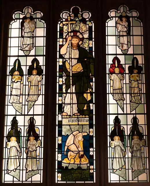 Stained glass window featuring Jesus Christ, angels, and a kneeling figure in a religious scene.