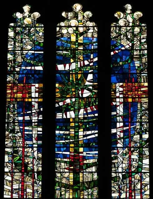 Colorful abstract stained glass window with three vertical panels and various geometric shapes and patterns.