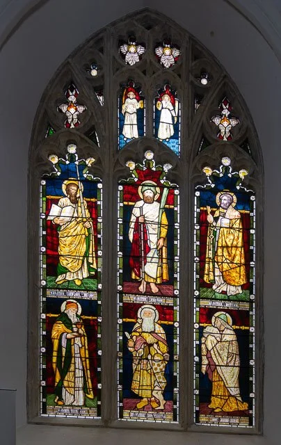 Colorful stained glass church window with biblical figures and decorative elements.