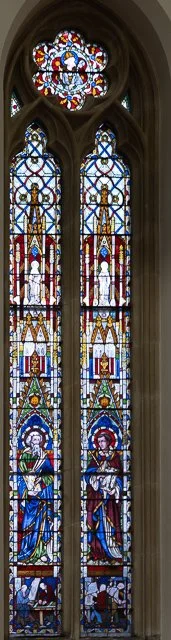 Colorful stained glass church window with intricate designs and religious figures.