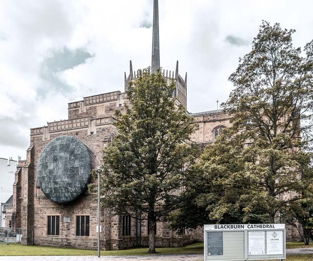 Exterior of Blackburn Cathedral with trees in front and signage