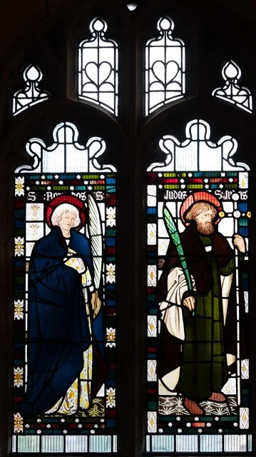 Two stained glass windows depicting Jesus and a saint, with decorative architectural elements at the top.