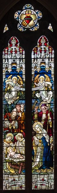 Stained glass window depicting religious figures and scenes from Christian faith, including angels, saints, and biblical icons.