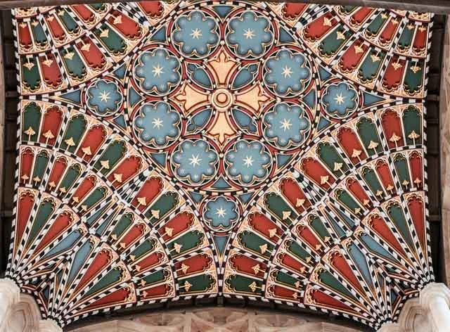 Decorative ceiling with colorful, intricate patterns resembling stylized floral and geometric motifs in blue, red, green, and cream.