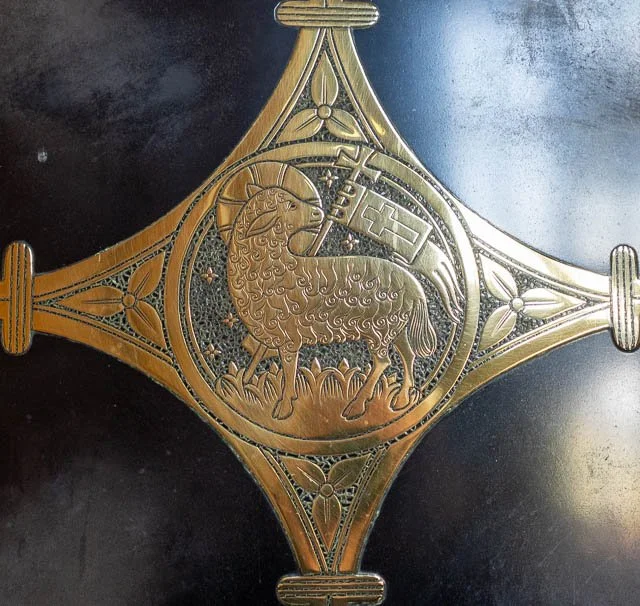 Decorative metal emblem with a central lion facing left, surrounded by intricate patterns and geometric designs.