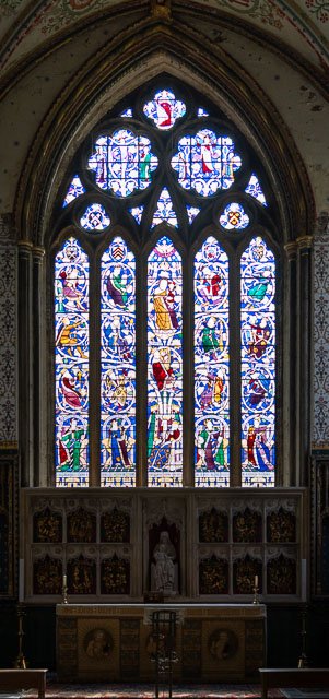 Colorful stained glass window in a church with religious scenes and figures.