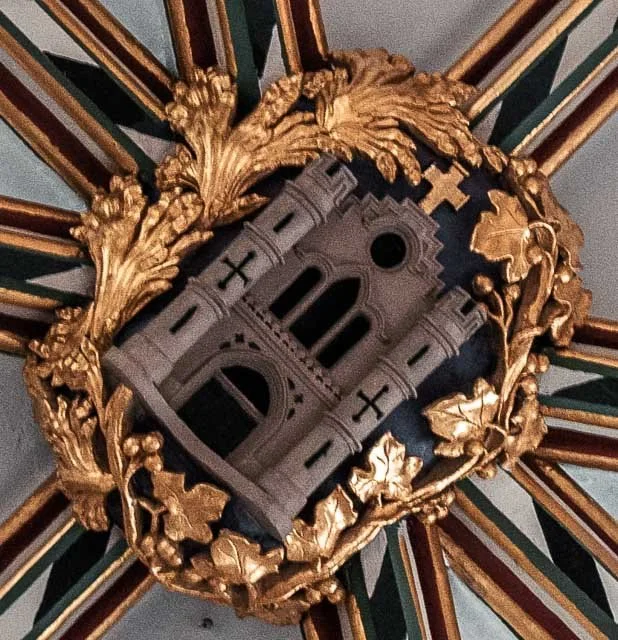 Ornate ceiling light fixture featuring a crown or castle design in a gold decorative frame.