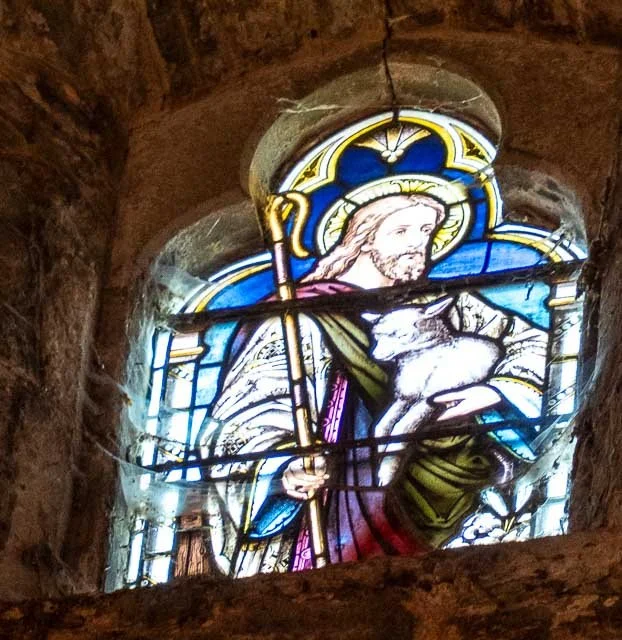 Stained glass window depicting Jesus Christ holding a lamb.