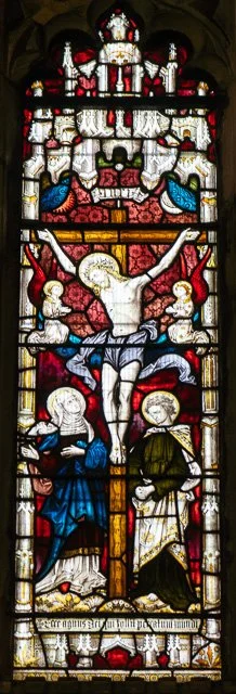 Stained glass window depicting Jesus Christ on the cross with saints and angels around him.