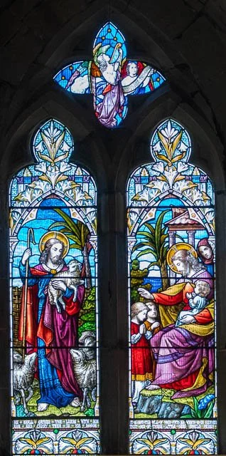Stained glass window depicting Jesus Christ with a lamb and a shepherd, and the Holy Spirit with a dove, in a church.