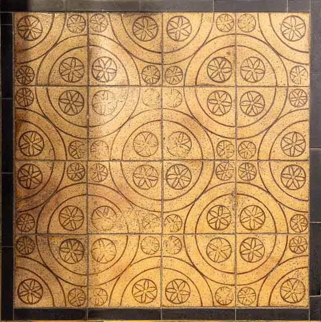 Decorative ceramic tiles with a circular geometric pattern in brown on a yellow background.