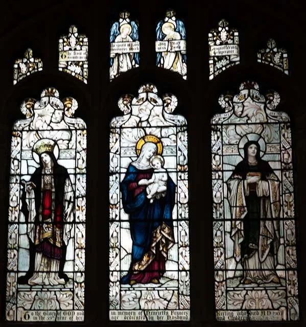 Stained glass windows depicting the Virgin Mary holding baby Jesus, with saints on either side.
