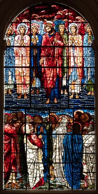 Stained glass window depicting Jesus Christ surrounded by angels and disciples.