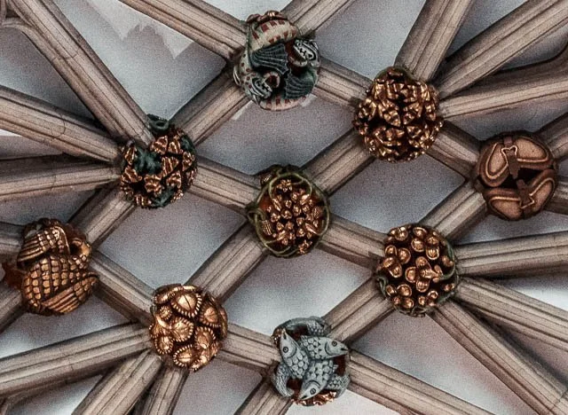 Decorative ceiling with woven rattan or wood strips forming a lattice pattern, adorned with small painted ornaments and figurines.