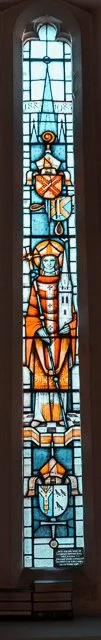 Colorful stained glass window featuring geometric shapes and two human figures, with a cross at the bottom and decorative elements in blue, orange, and yellow.