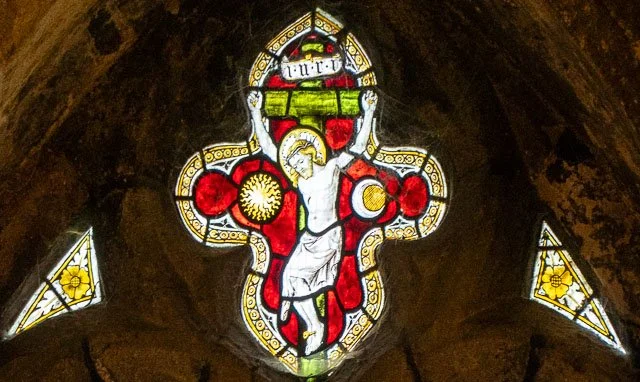 Stained glass window depicting Jesus Christ on the cross inside a church.