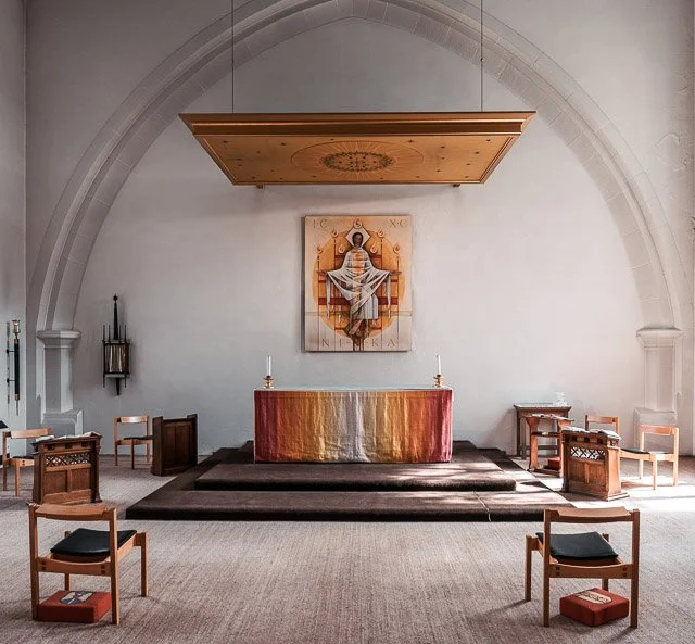 Christian altar with a golden cloth, candles, and a religious icon of the Virgin Mary in a small chapel with white walls and an arched ceiling.